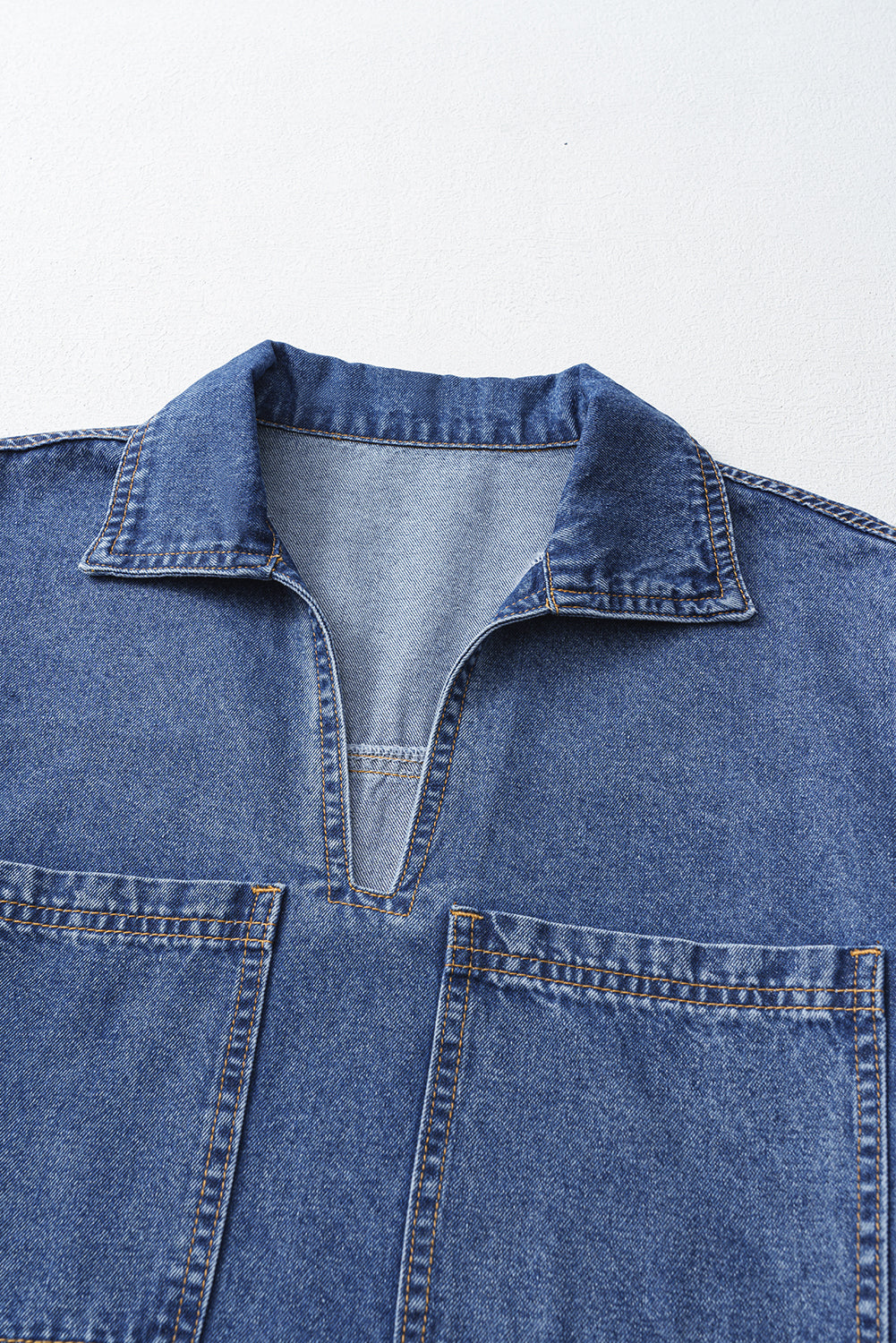 Close-up of blue denim shirt with collar, V-neck opening, and front patch pockets