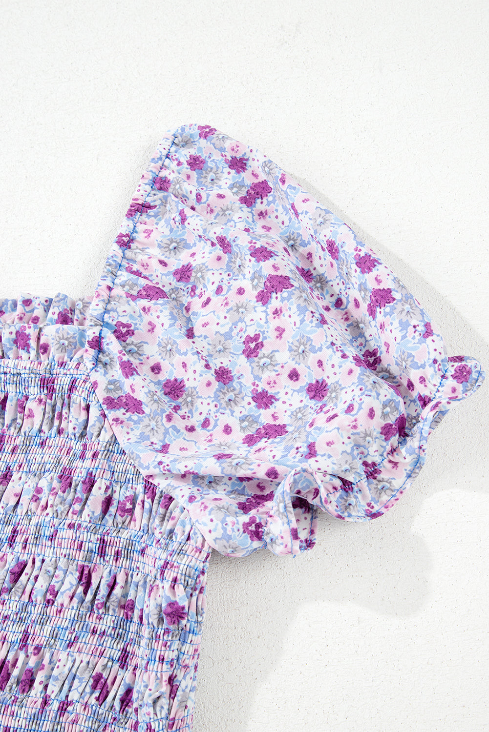 Close-up of puff sleeve floral dress in purple and blue with smocked waist detail