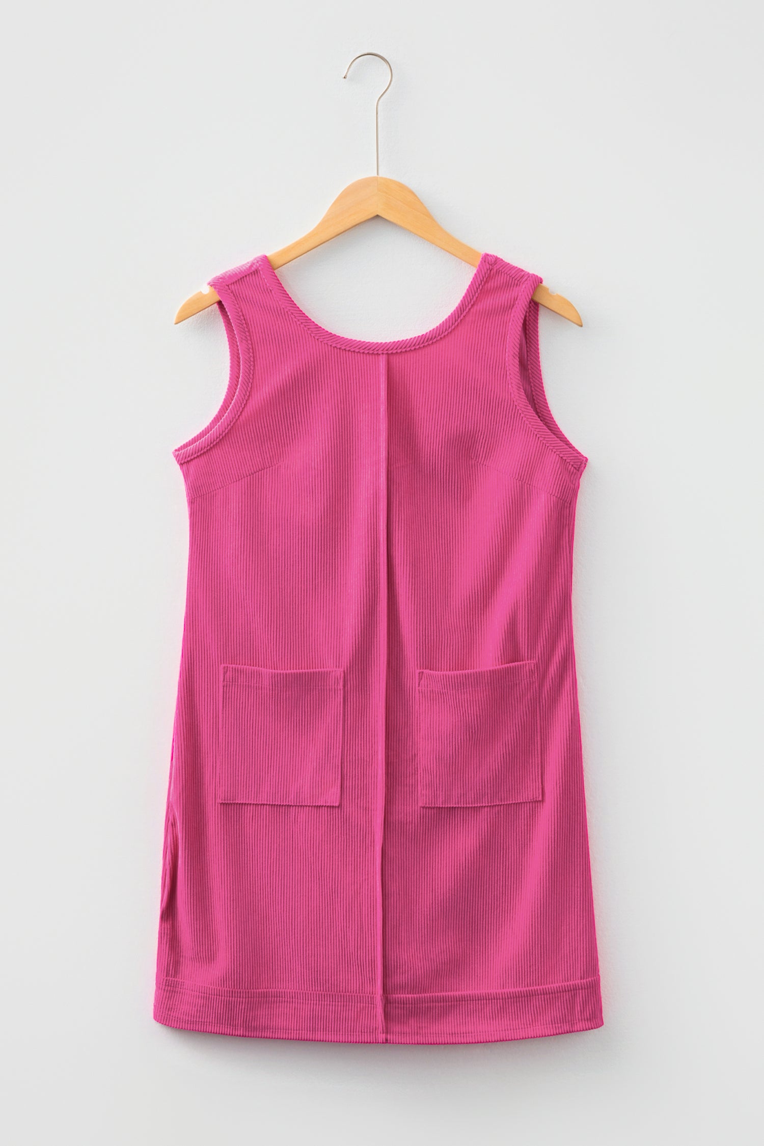Pink sleeveless corduroy dress with front pockets on hanger