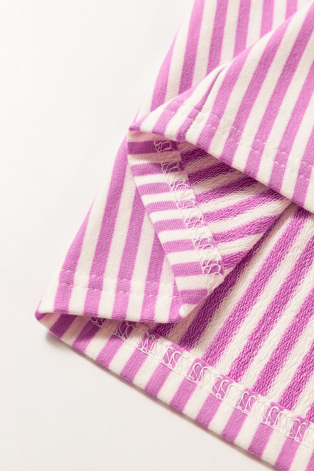 Close-up of pink and white striped fabric with detailed stitching, soft knit textile