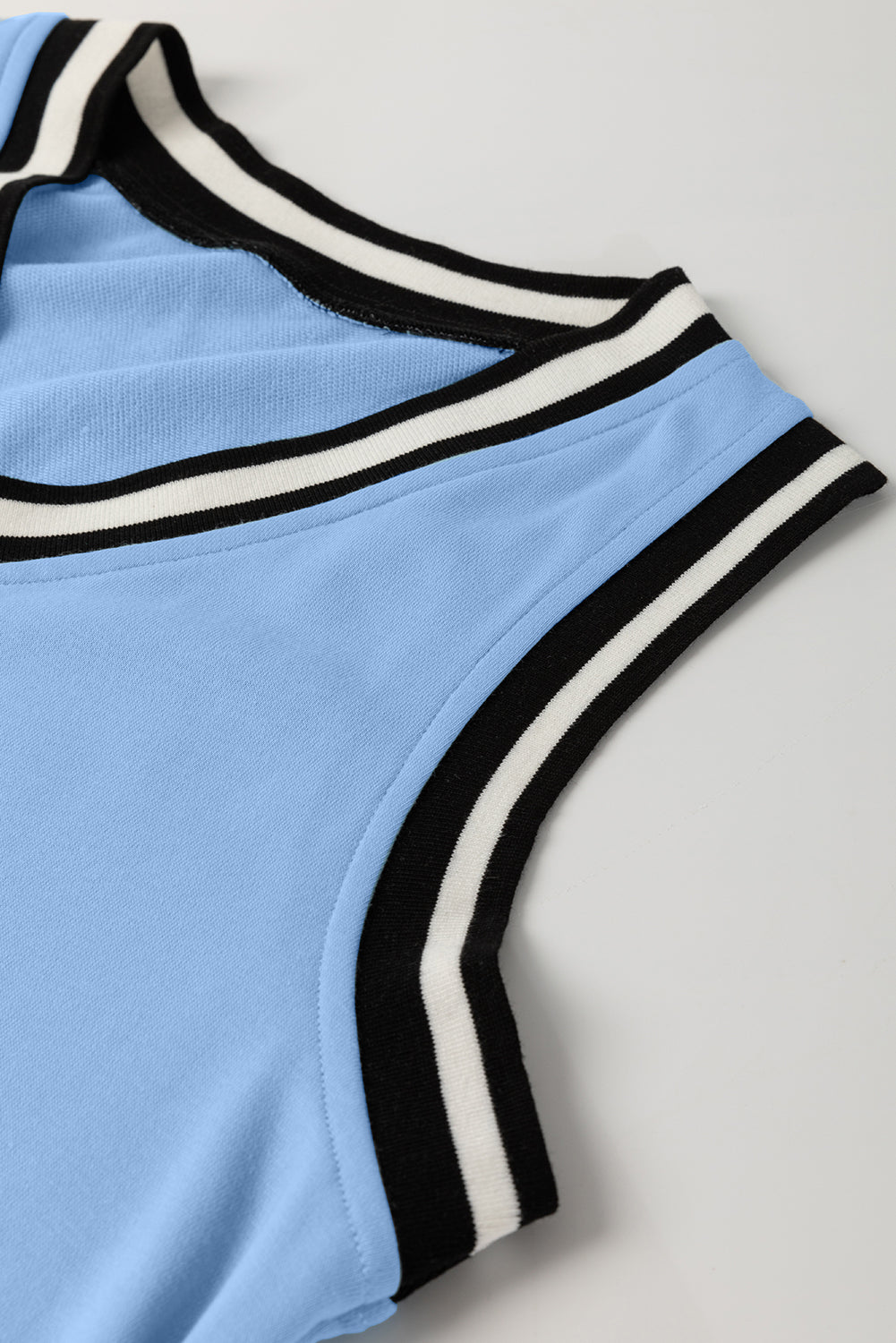 Close up of light blue sleeveless top with black and white striped ribbed trim