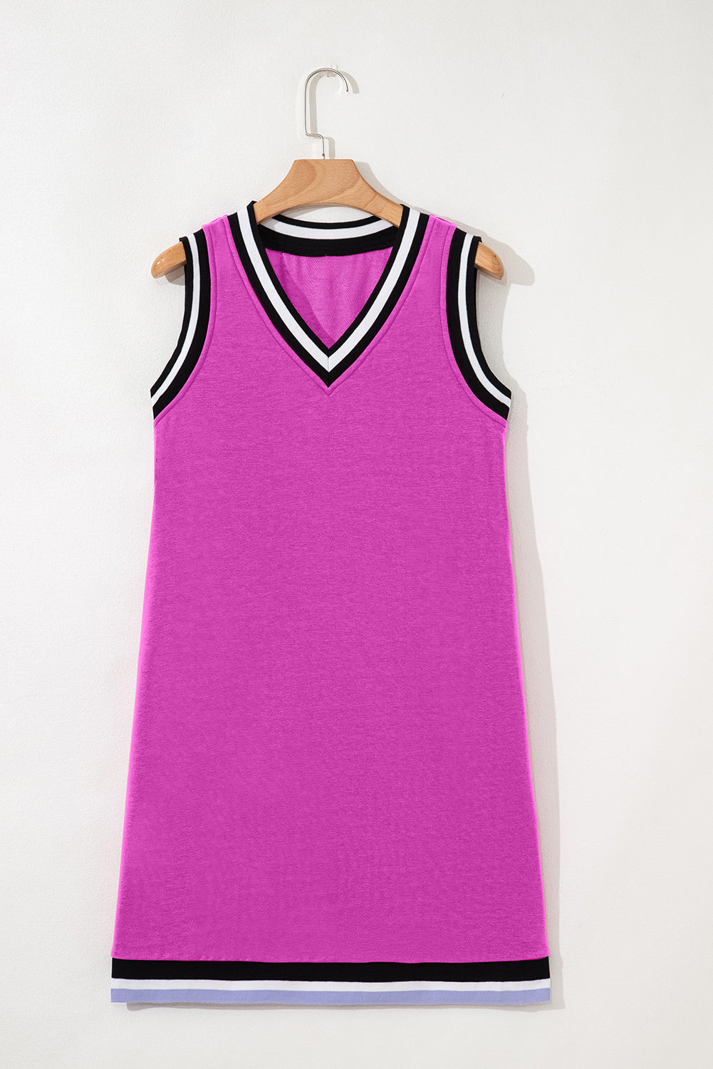 Sleeveless pink shift dress with black and white striped V-neck and hem on hanger