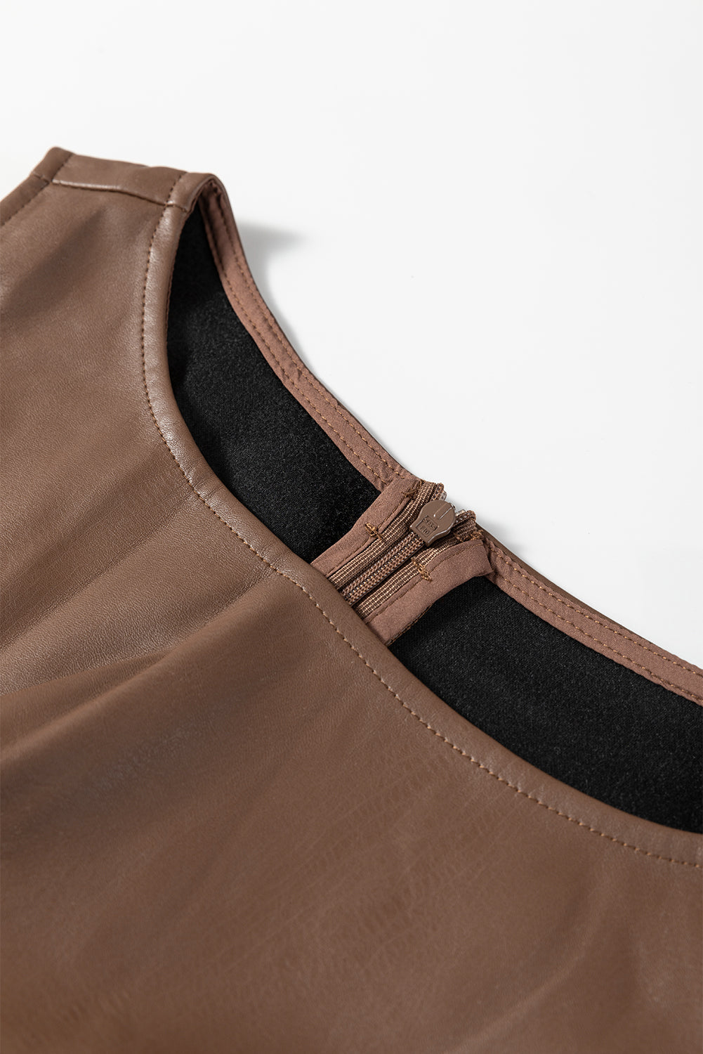Close-up of brown faux leather dress neckline with back zipper on white background
