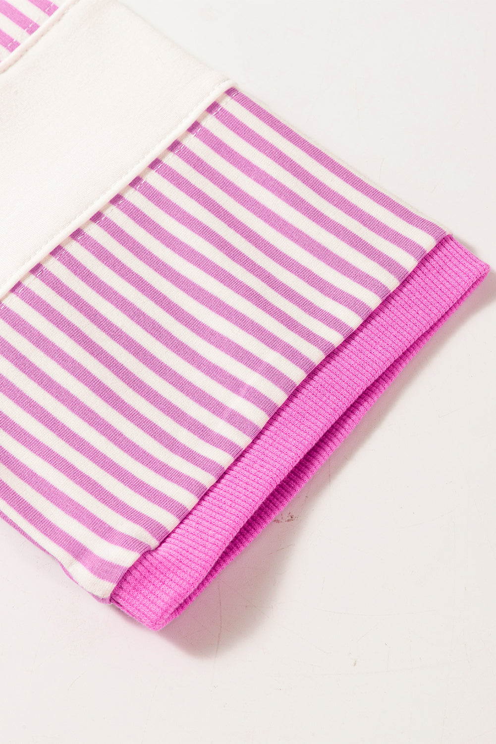 Close-up of a long sleeve with pink and white stripes and ribbed pink cuff