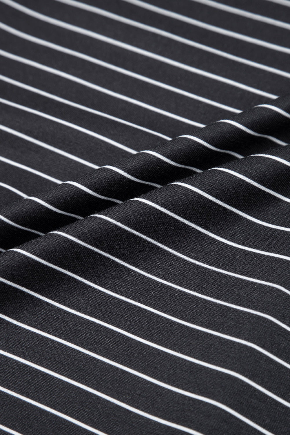 Close-up of black fabric with white vertical pinstripes, folded surface texture