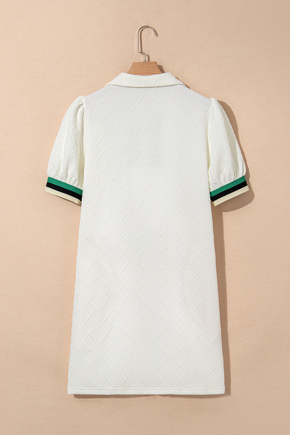 White textured short-sleeve dress with green and black striped cuffs, back view on hanger
