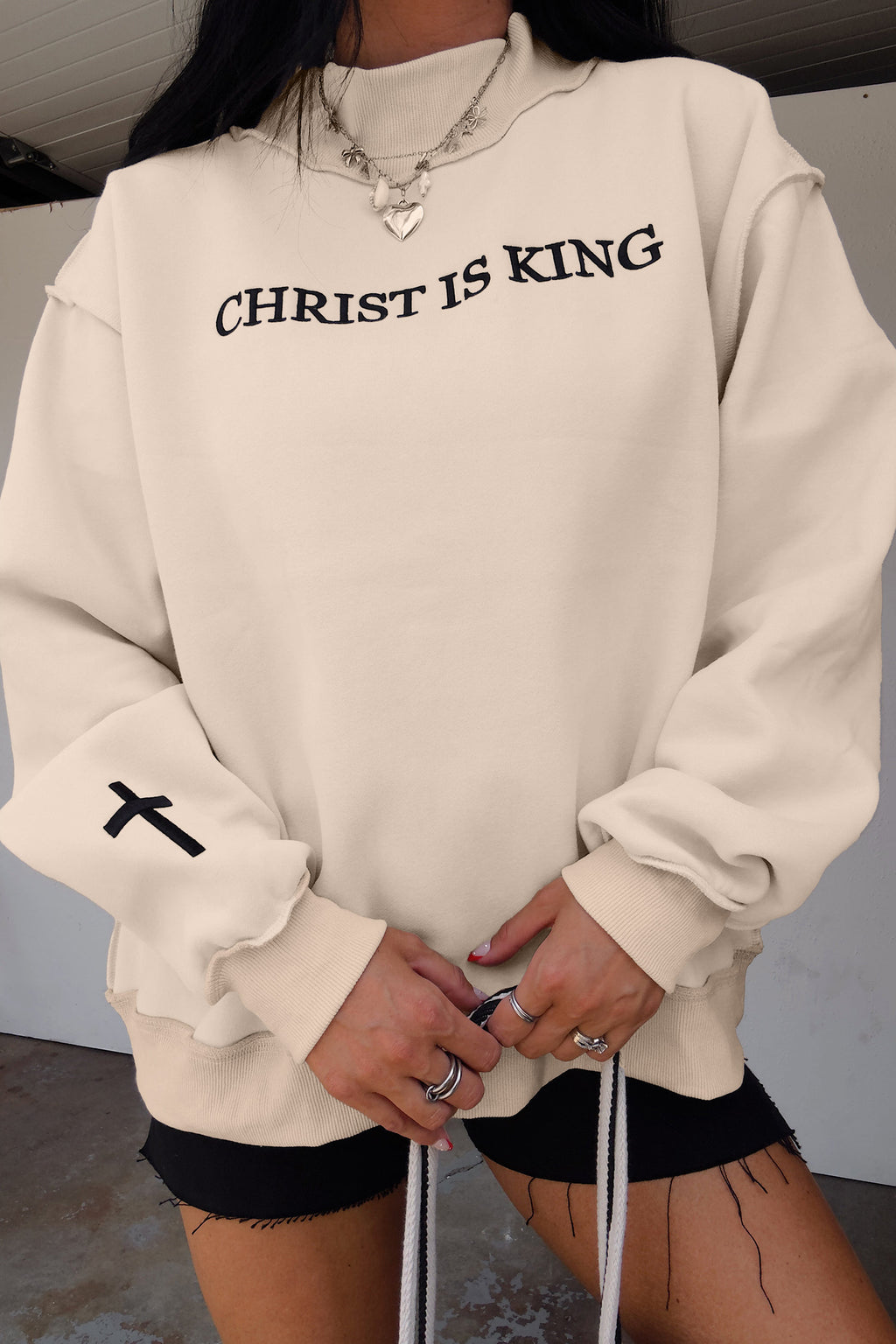 Бежов oversize суитшърт с надпис CHRIST IS KING и черен кръст на ръкава, отпред, с висока яка