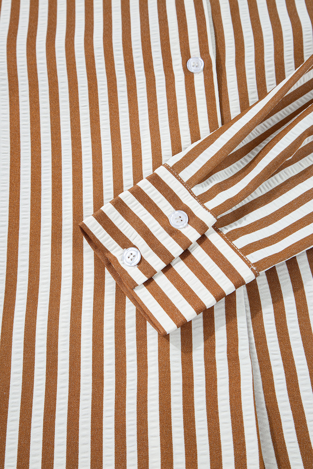 Brown and white vertical striped shirt sleeve with white buttons, closeup