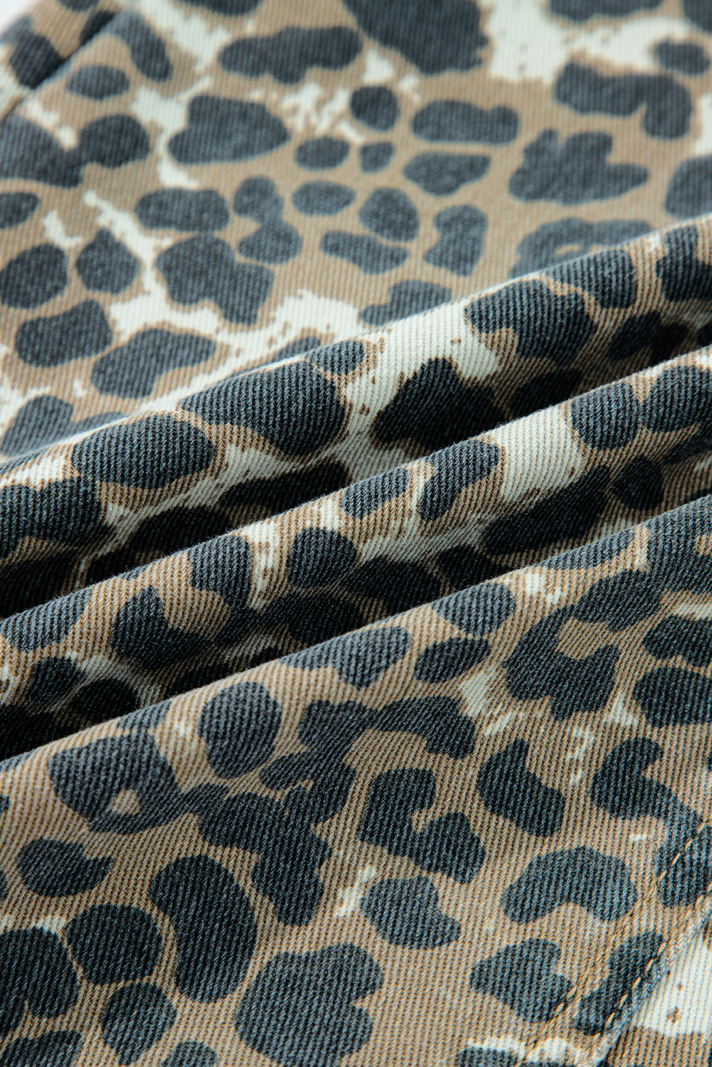 Close-up of leopard print fabric in brown, black, and beige, folded for texture detail