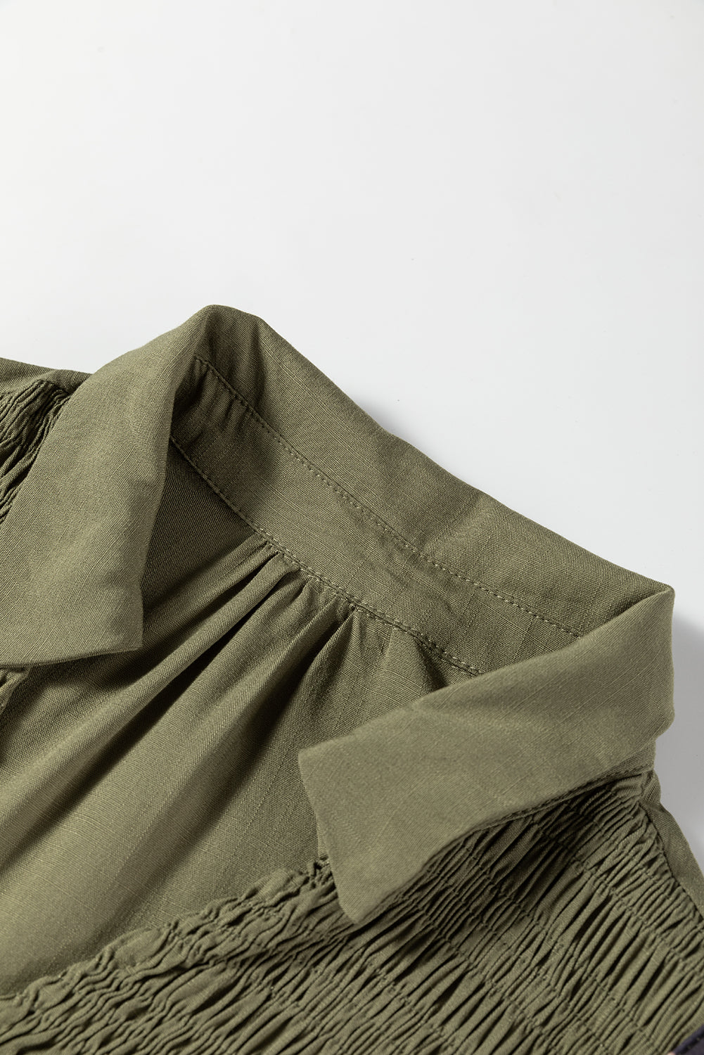 Olive green shirt collar with pleated detailing and textured fabric, close-up view
