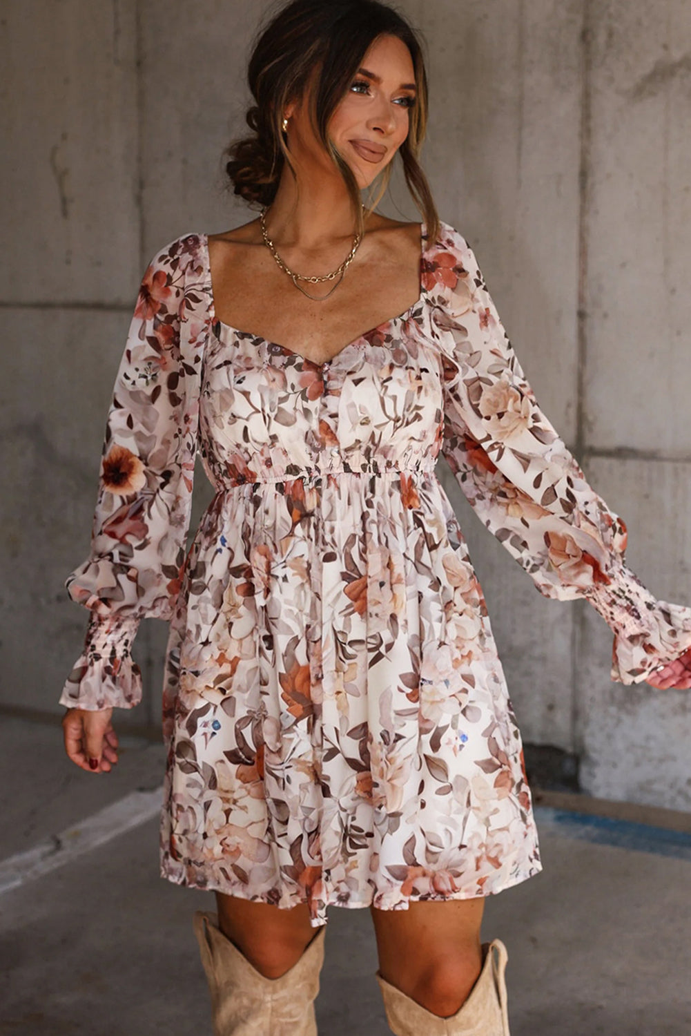 Woman wearing a long-sleeve floral mini dress with ruffled cuffs and neutral cowboy boots