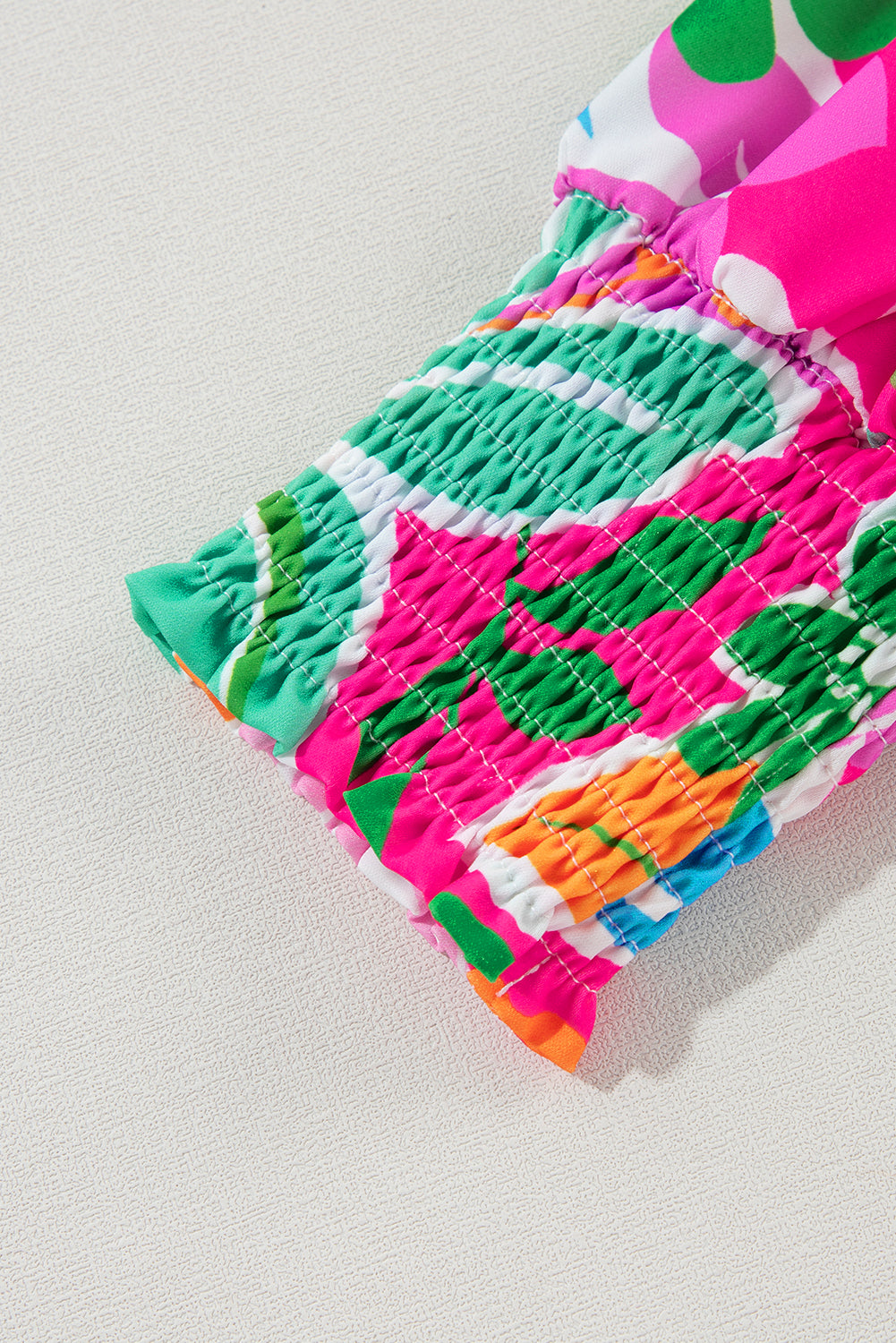 Close-up of a colorful floral sleeve with ruched elastic cuff on textured fabric