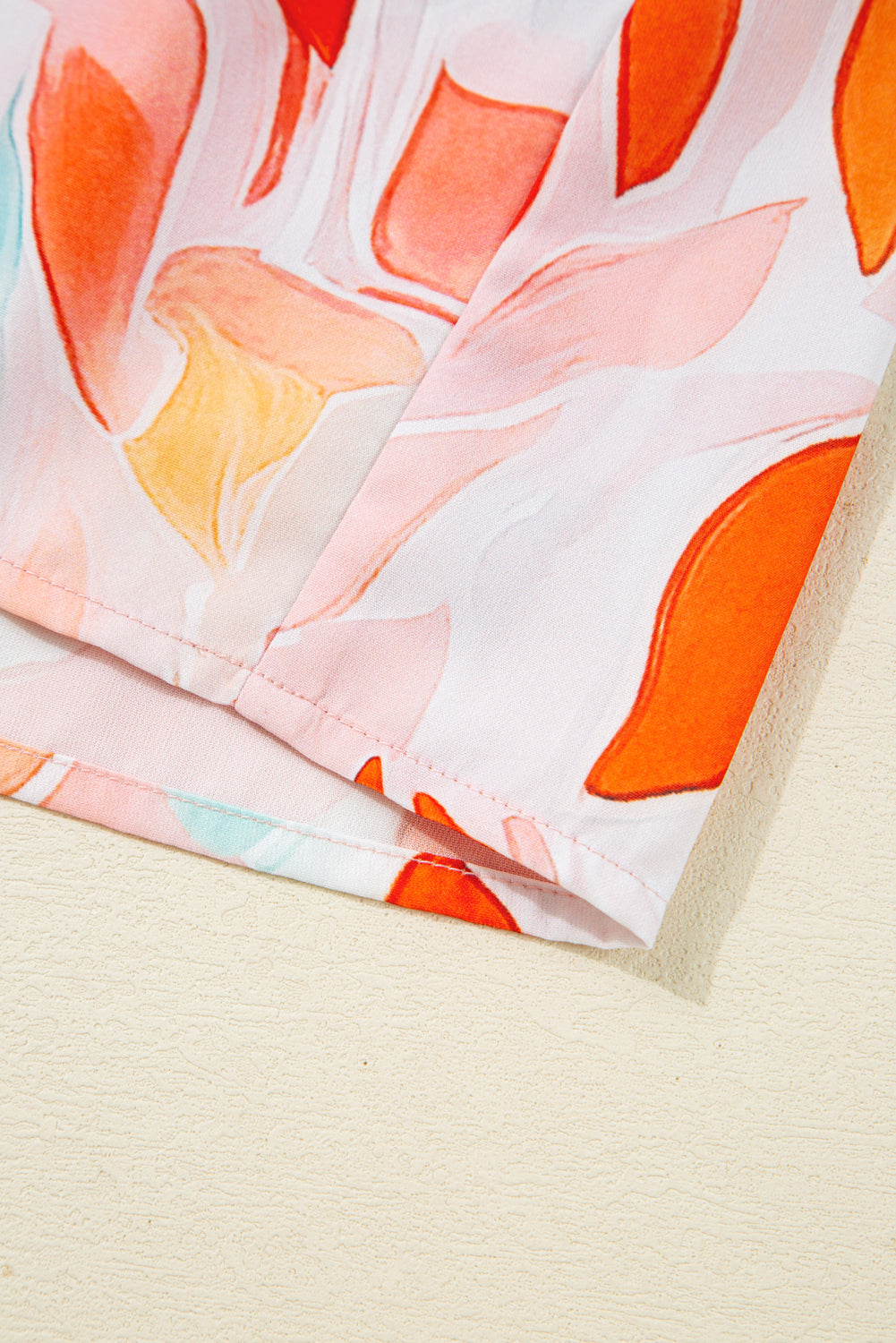 Close-up of fabric with colorful abstract floral print in orange, pink, and yellow hues