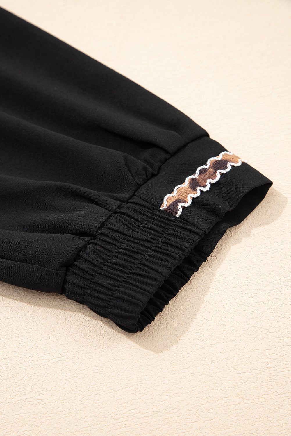 Black sleeve with elastic cuff and wavy brown embroidered trim detail