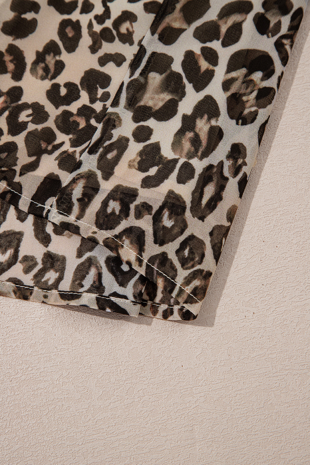 Close up of leopard print fabric with stitched edge, animal pattern textile detail