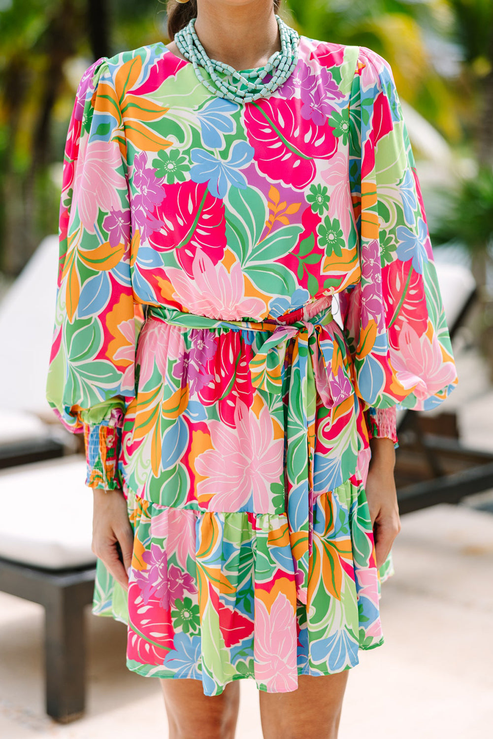Colorful floral print long sleeve dress with a belted waist, worn outdoors.