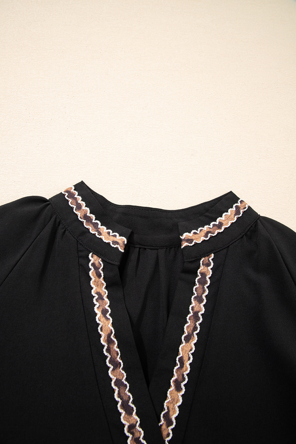 Black blouse with V-neck and brown zigzag embroidered trim on collar and neckline