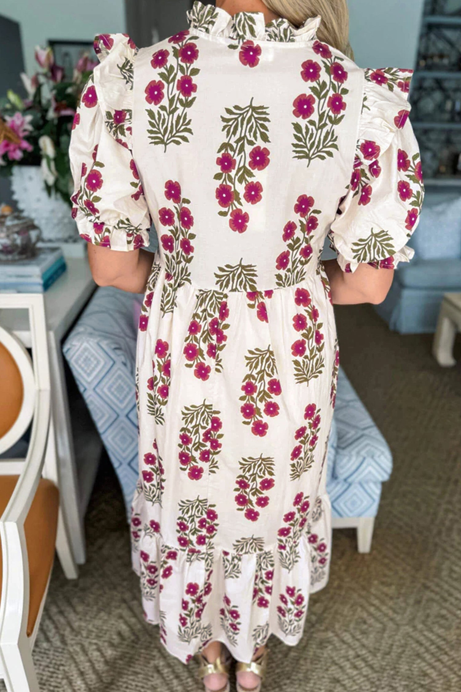Woman wearing a white floral print dress with ruffled sleeves in a cozy home setting