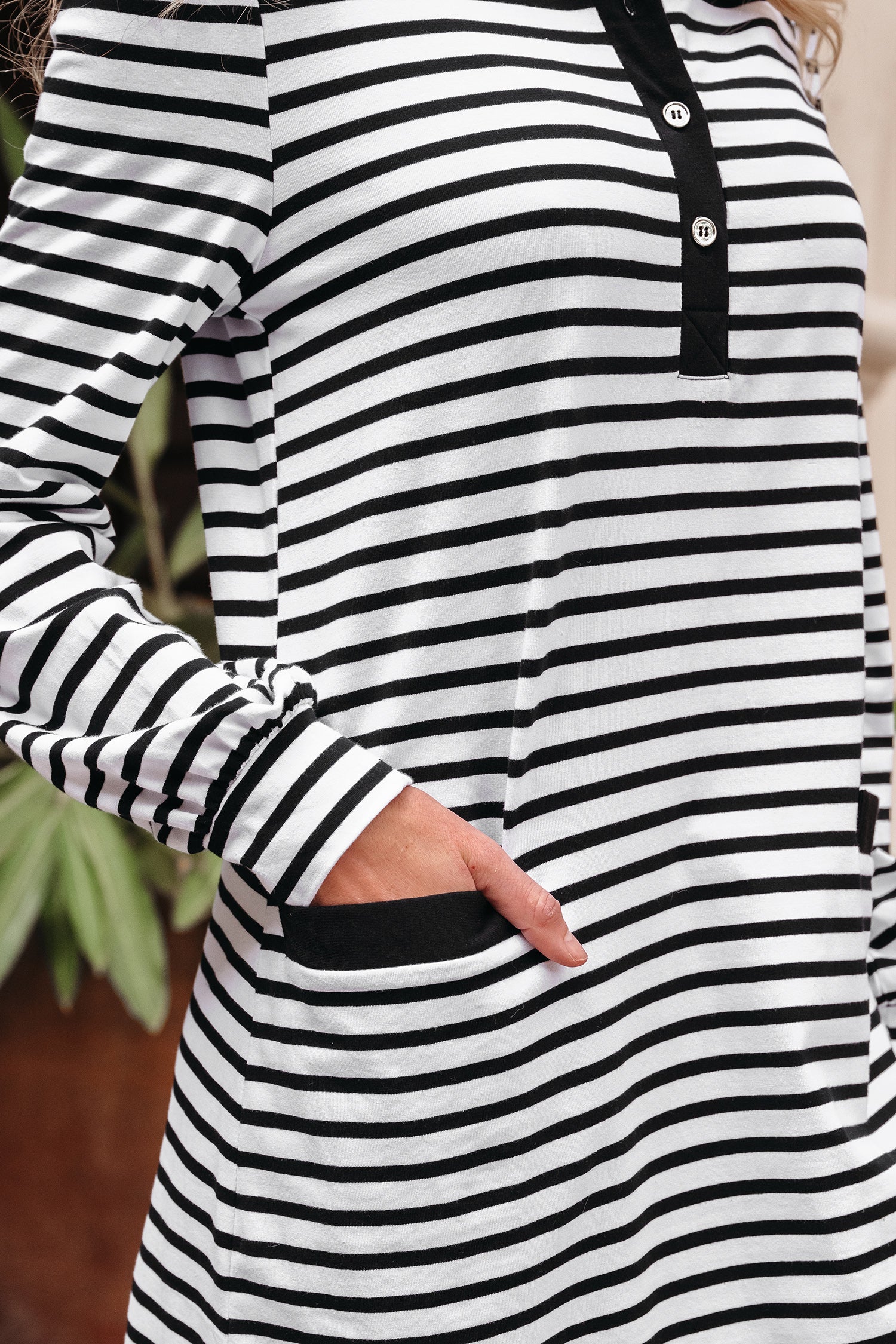Woman wearing a black and white striped long sleeve dress with buttons and pockets