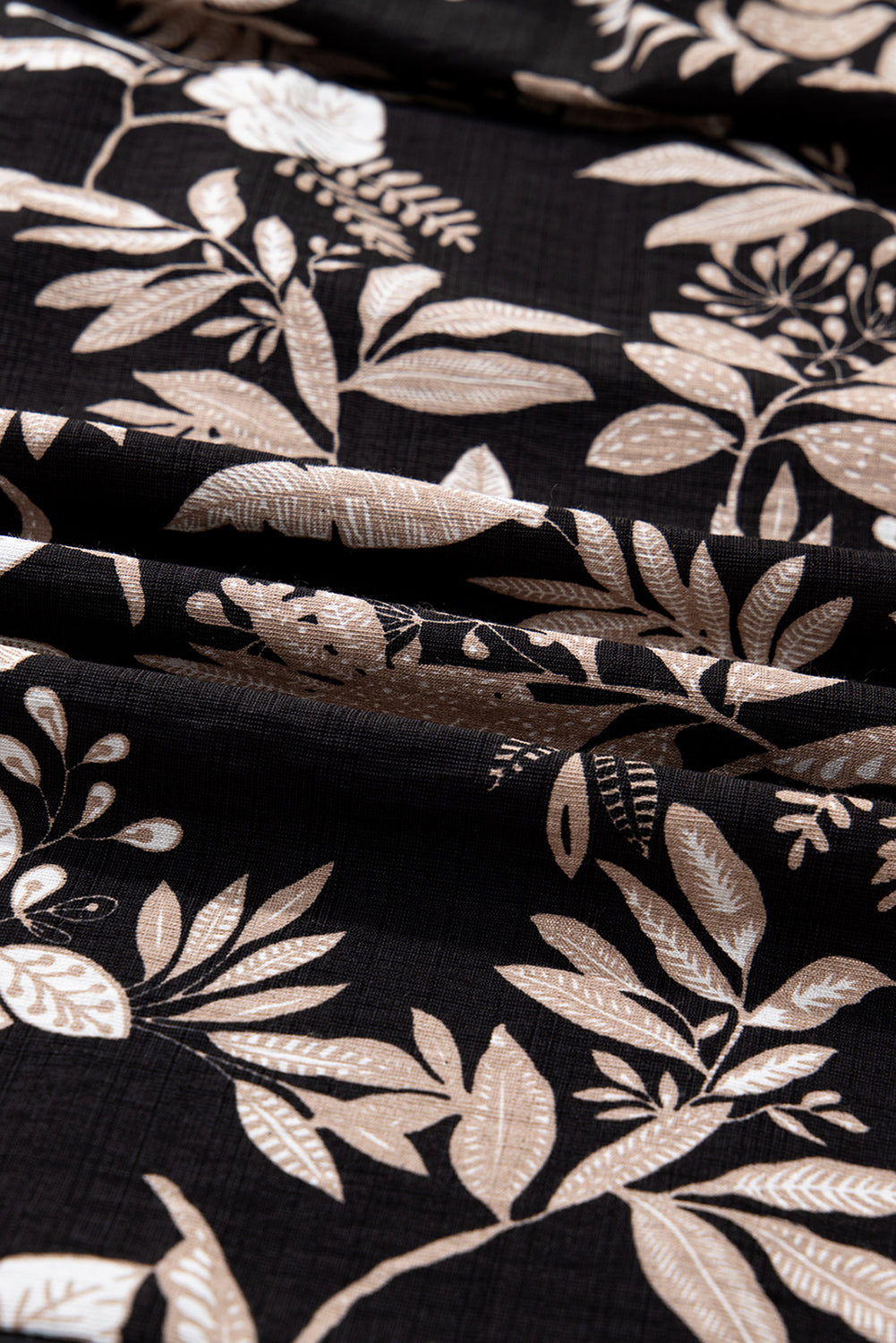 Black fabric with beige botanical floral print and textured surface