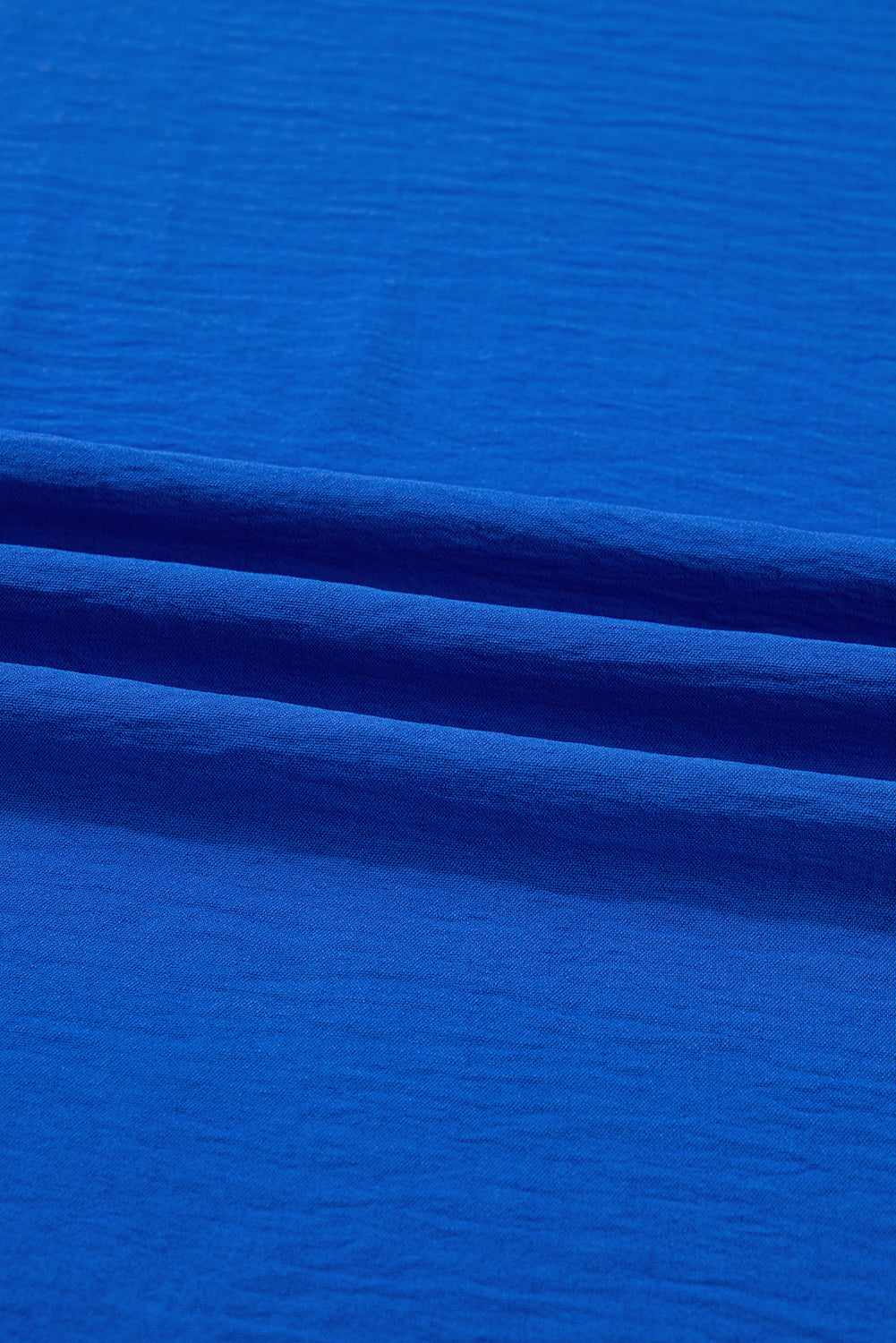 Bright blue textured fabric with soft folds and natural weave pattern