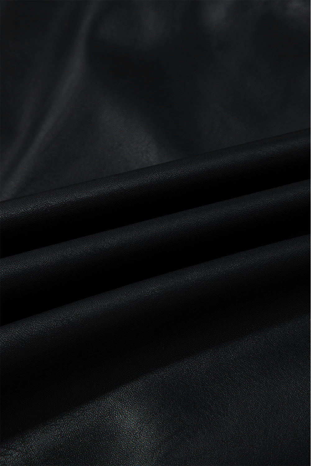 Close-up of smooth black faux leather fabric with subtle texture and soft folds