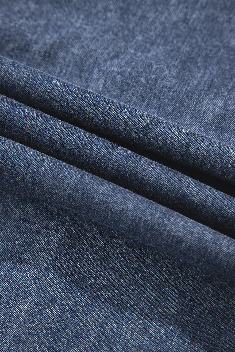 Close-up of folded blue denim fabric, textured jeans material.