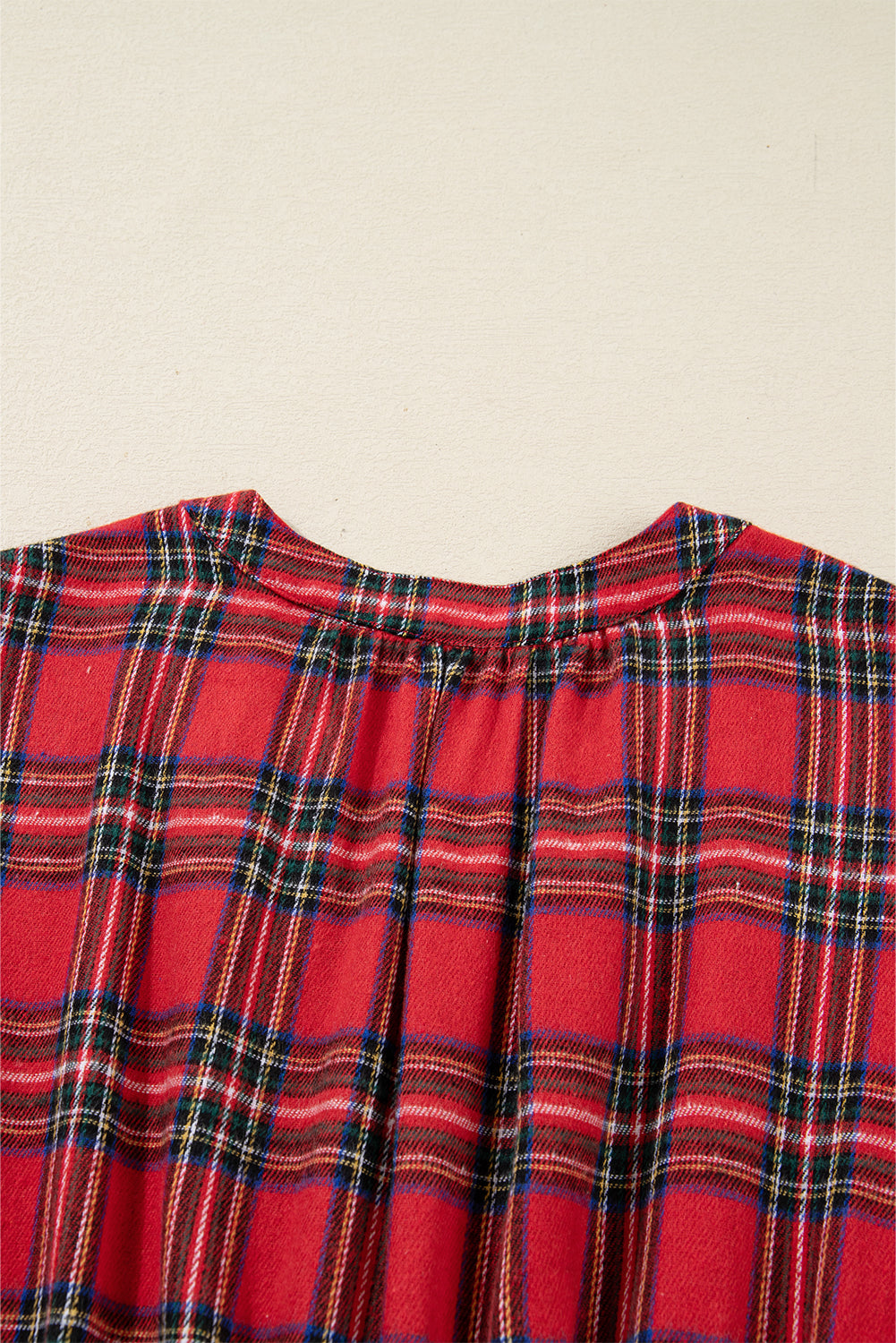 Close-up of red plaid flannel shirt collar and pleated back detail
