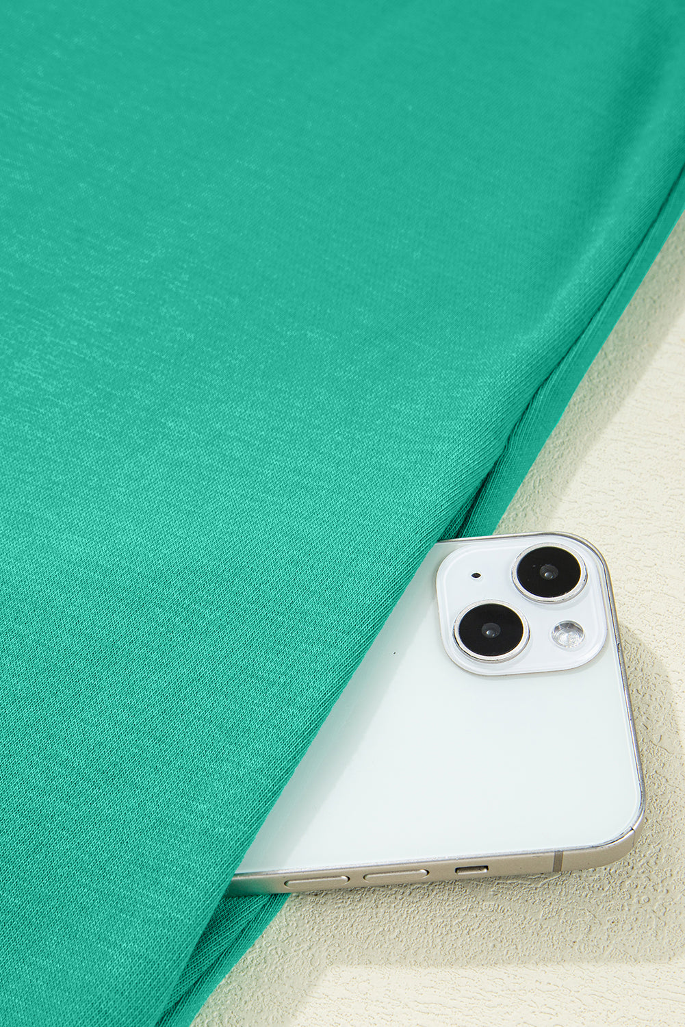Turquoise garment pocket with smartphone partially visible, close-up fabric detail