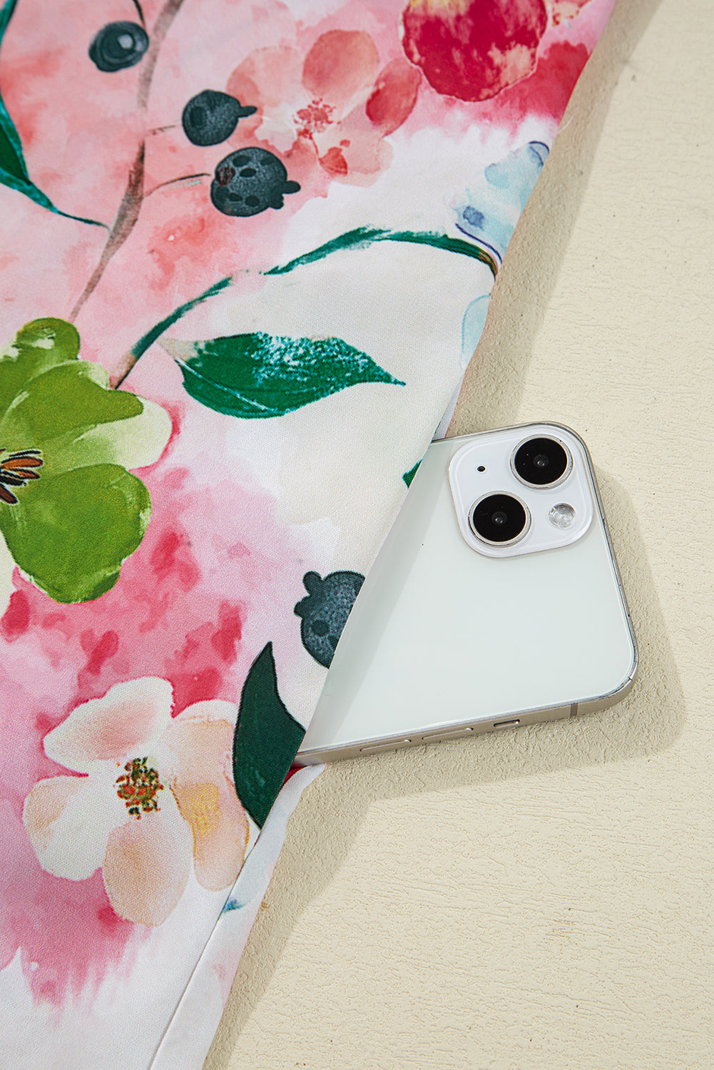 White smartphone partially in pocket of pink floral fabric garment, close-up view