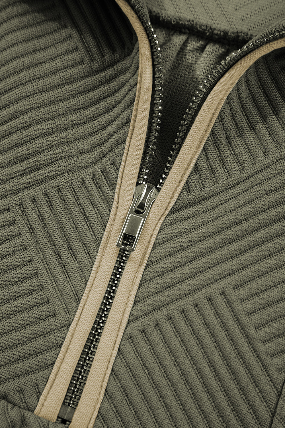 Close-up of olive green textured fabric with a silver zipper