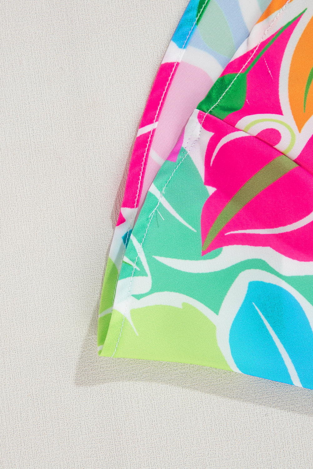 Close up of colorful floral patterned fabric with green, blue, pink, and orange hues