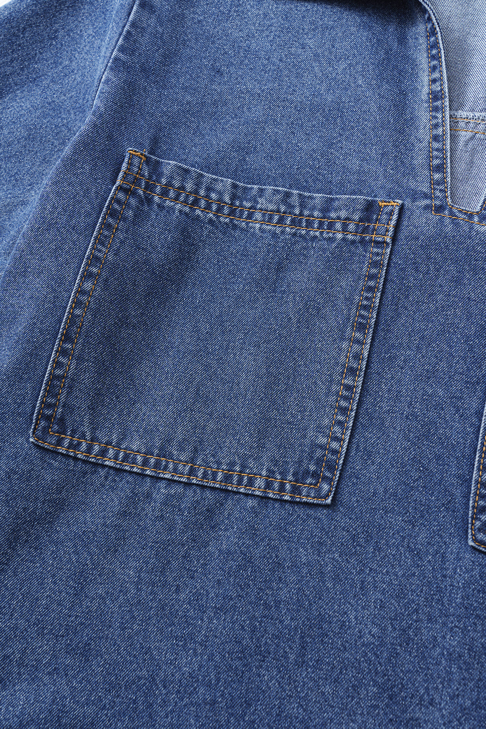 Close-up of a blue denim shirt with a square front pocket and visible stitching