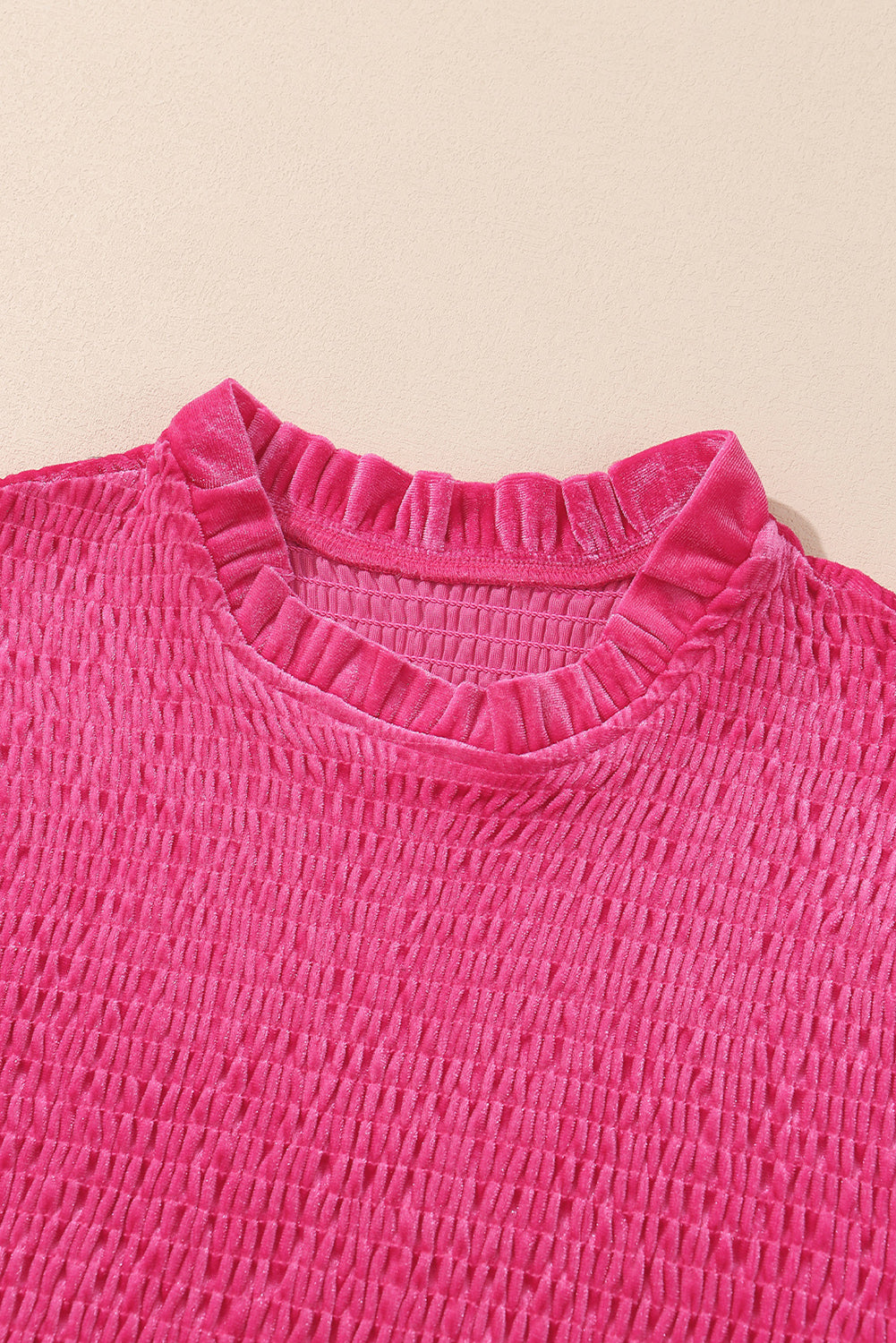 Textured hot pink velvet top with gathered high neckline on beige background