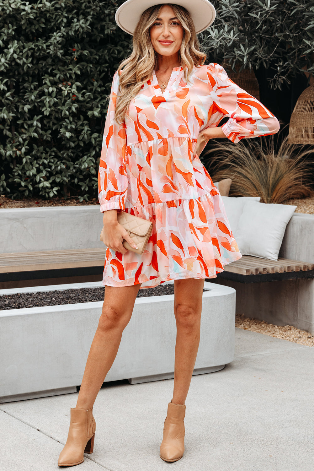 Woman in a colorful long sleeve mini dress, beige hat, and boots outdoors